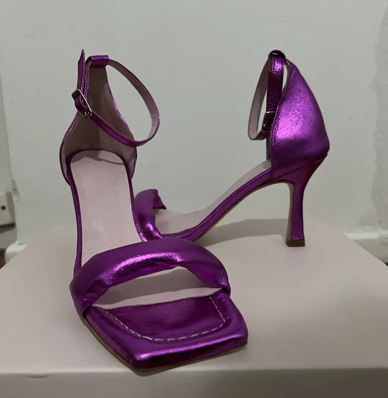 Sandalias de fiesta color violeta metalizado con taco fino y pulsera al tobillo. Ideales para eventos y ocasiones especiales.