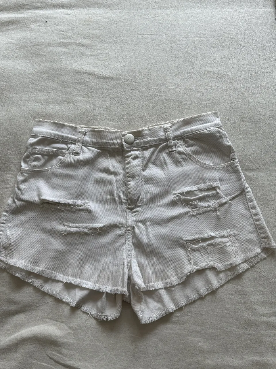 Short de jean blanco con roturas y flecos en el borde. Talle 30, ideal para un look casual y moderno.