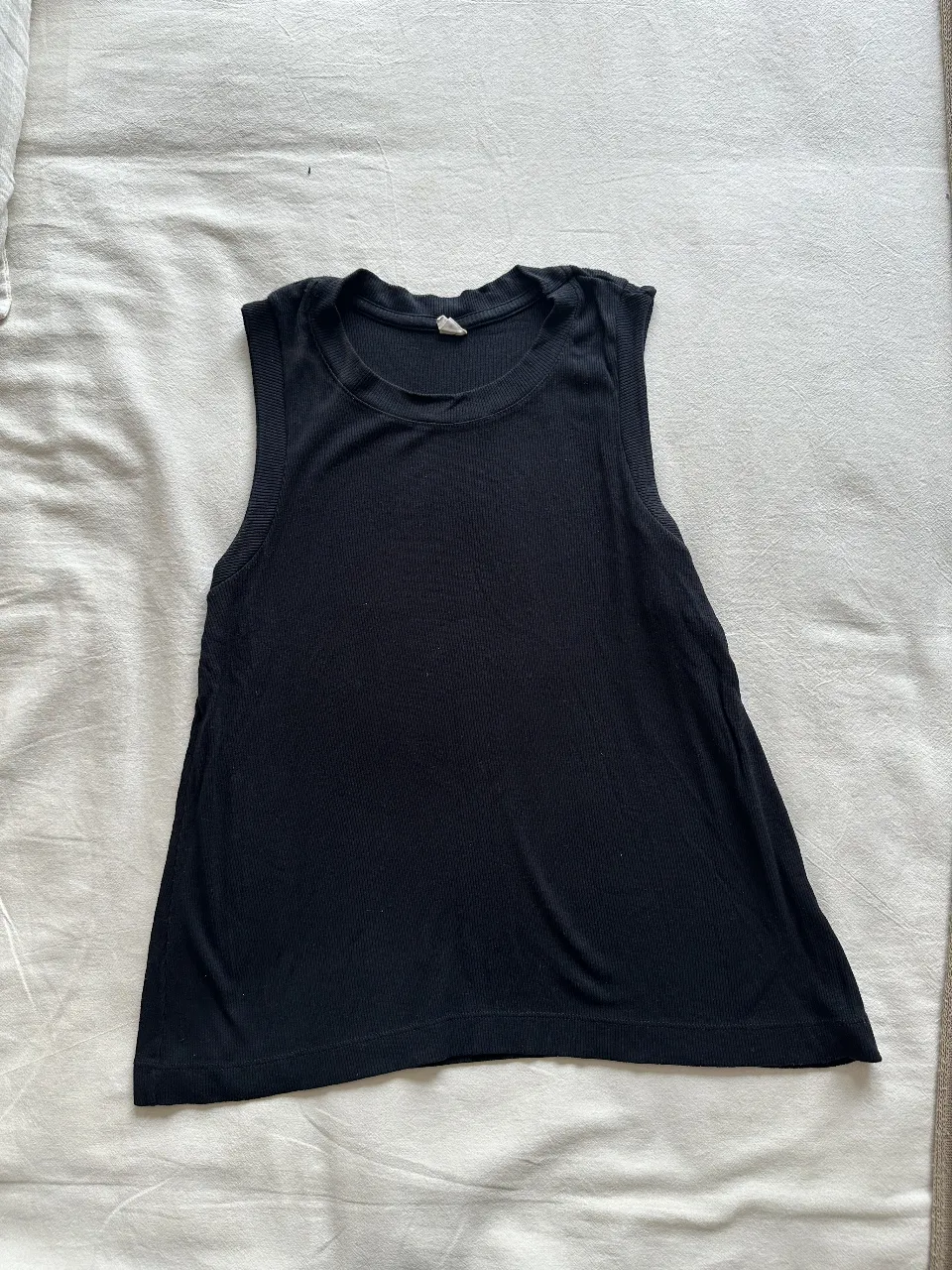 Musculosa negra de tejido de punto, ideal para el verano. Corte recto y escote redondo. Perfecta para un look casual y cómodo.