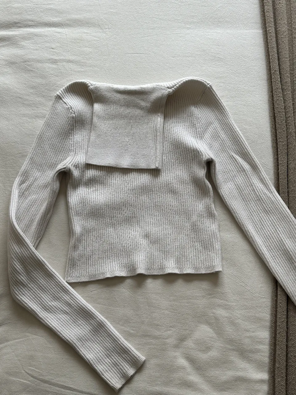 Sweater de cuello alto para mujer, de color blanco. Confeccionado en tejido de punto acanalado, manga larga y detalle de solapa en el cuello. Ideal para un look casual y elegante.
