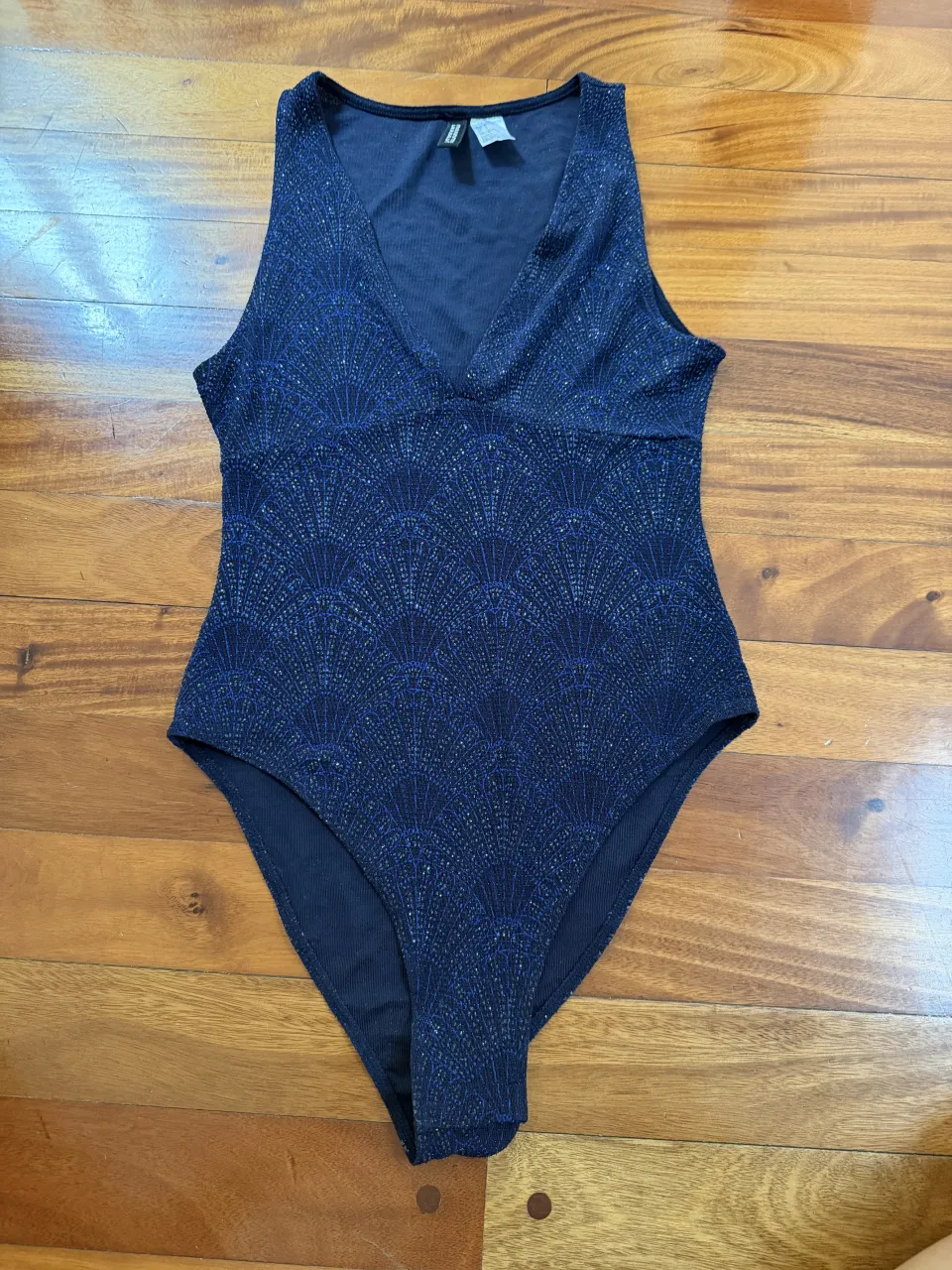 Body de tela con brillos y estampado geométrico en forma de abanico. Escote en V y sin mangas.