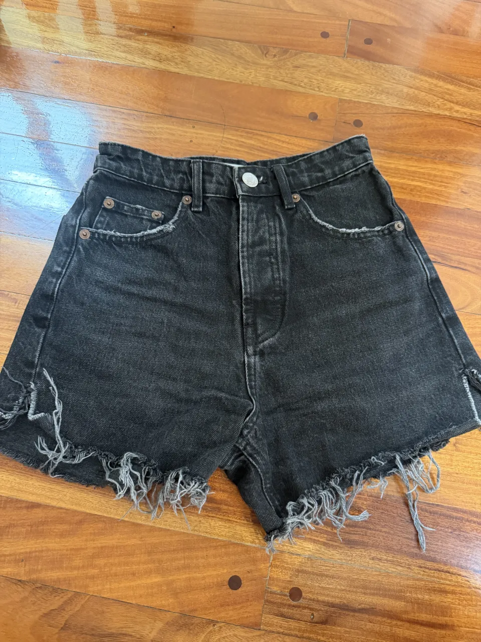 Shorts de jean negros con roturas y detalles desflecados en los bordes. Tiro alto, ideales para un look canchero y moderno.