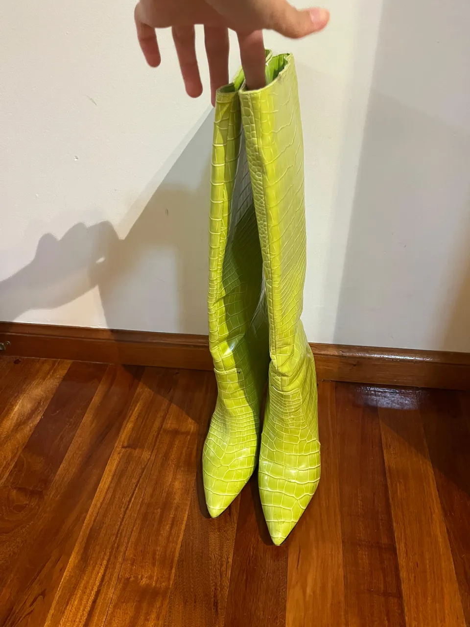 Botas de caña alta color verde lima, con textura de cocodrilo y taco fino. Ideales para un look audaz y a la moda.