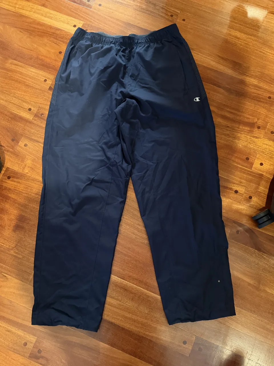 Pantalón de entrenamiento azul marino con logo de Champion en la pierna derecha. Cintura elástica con cordón interno. Bolsillos laterales.