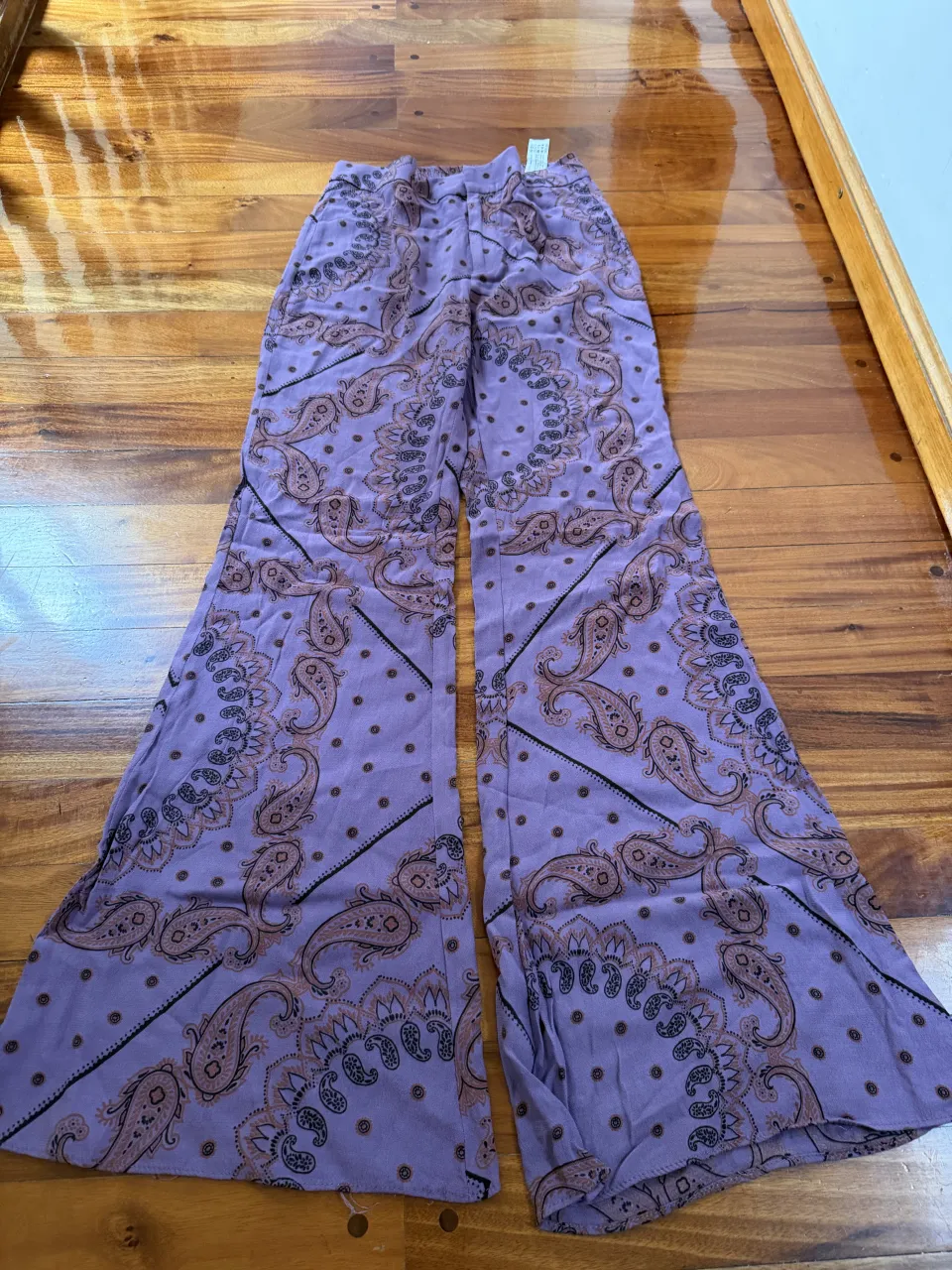 Pantalón largo de tela con estampa paisley en tonos lilas y marrones. Cintura elastizada.