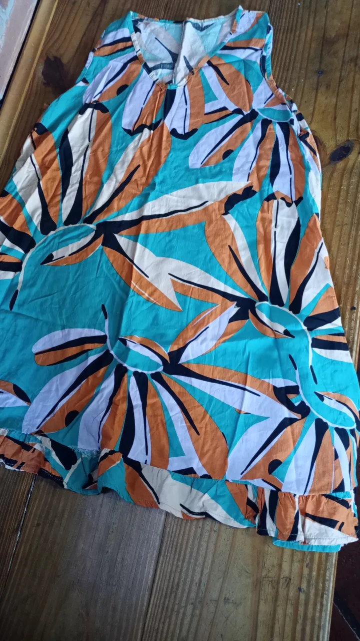 Vestido corto de mujer con estampado floral en tonos turquesa, naranja, blanco y negro. Ideal para el verano, este vestido sin mangas es perfecto para un look casual y fresco.