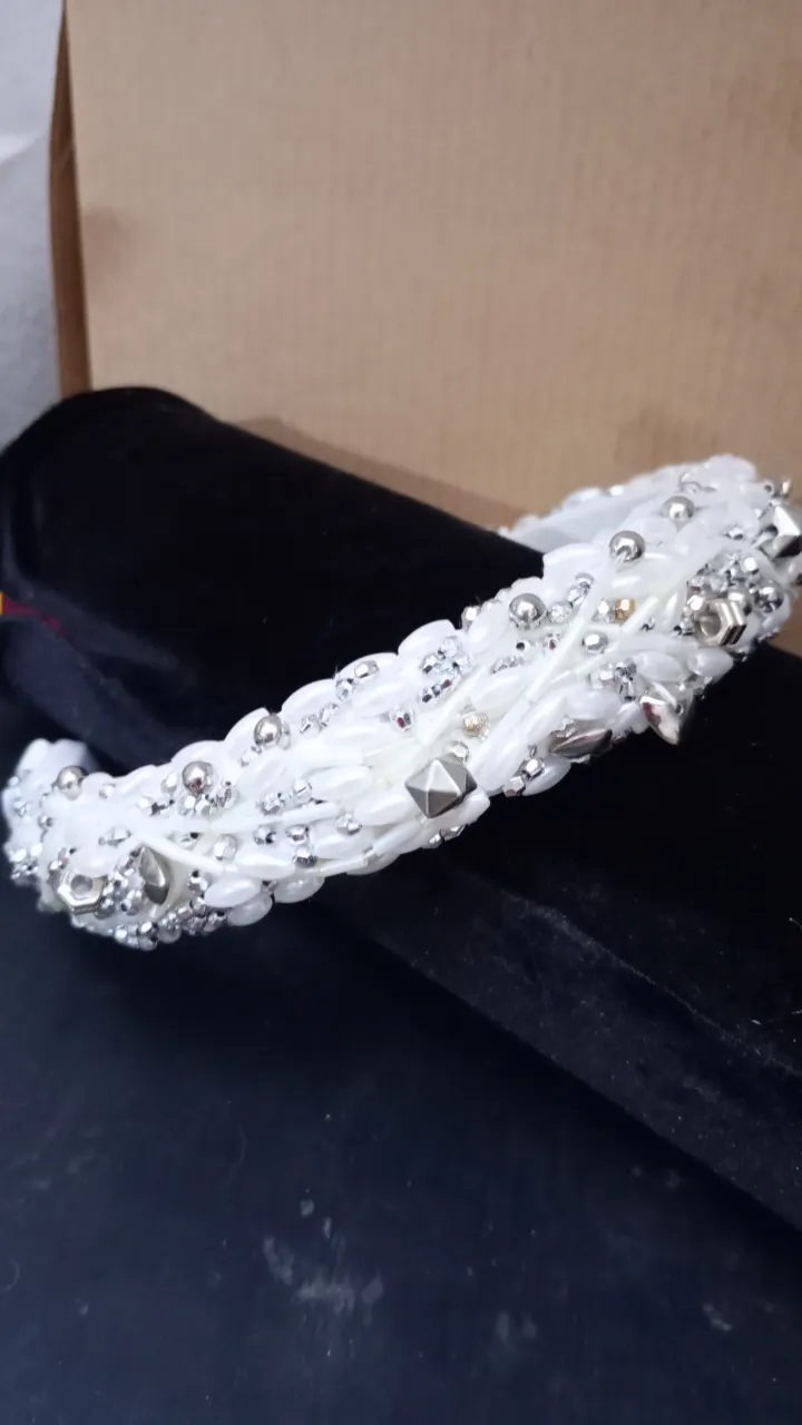 Diadema blanca adornada con detalles plateados y perlas, ideal para eventos especiales o para darle un toque elegante a tu look.