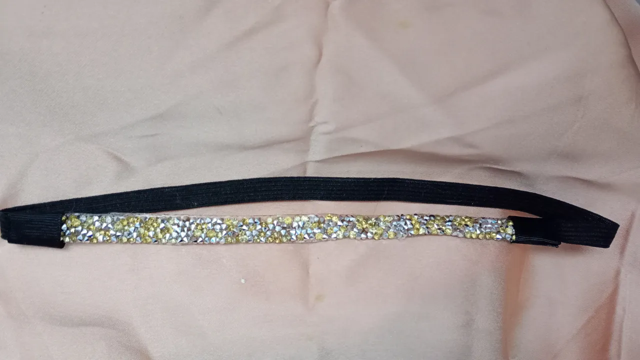 Vincha elástica negra con apliques de strass en tonos dorados y plateados. Ideal para darle un toque de brillo a cualquier look.