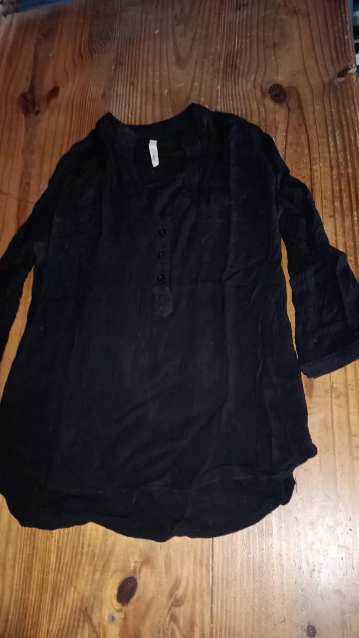 Blusa negra de manga larga con botones y cuello en V. Ideal para un look casual y versátil.