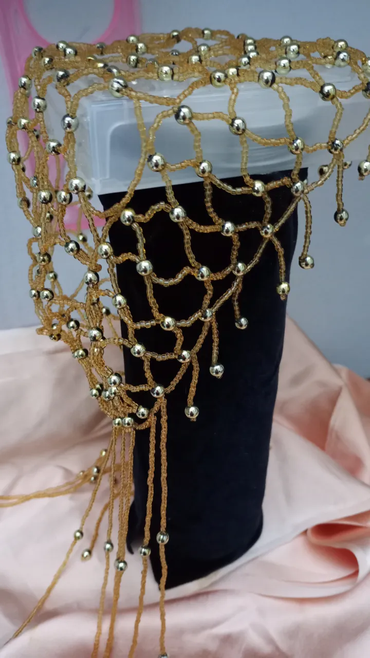 Diadema dorada artesanal, ideal para eventos especiales o para darle un toque único a tu look. Diseño intrincado con detalles de cuentas.