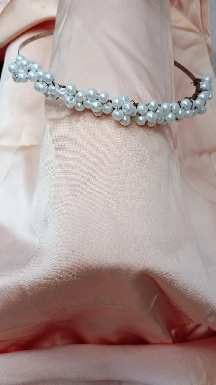 Hermosa vincha para el pelo adornada con perlas blancas, ideal para complementar cualquier look femenino y elegante.
