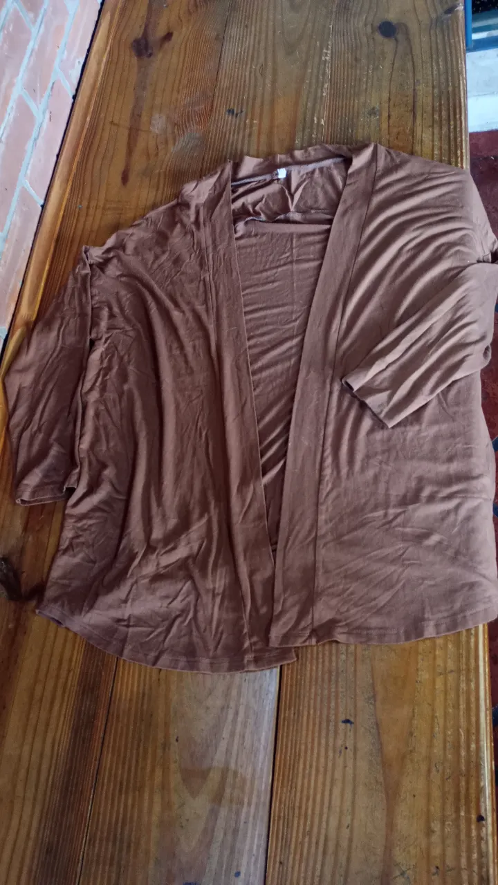 Cardigan marrón de tejido ligero, ideal para usar como abrigo ligero en cualquier ocasión. Su diseño abierto y mangas amplias lo hacen cómodo y versátil.