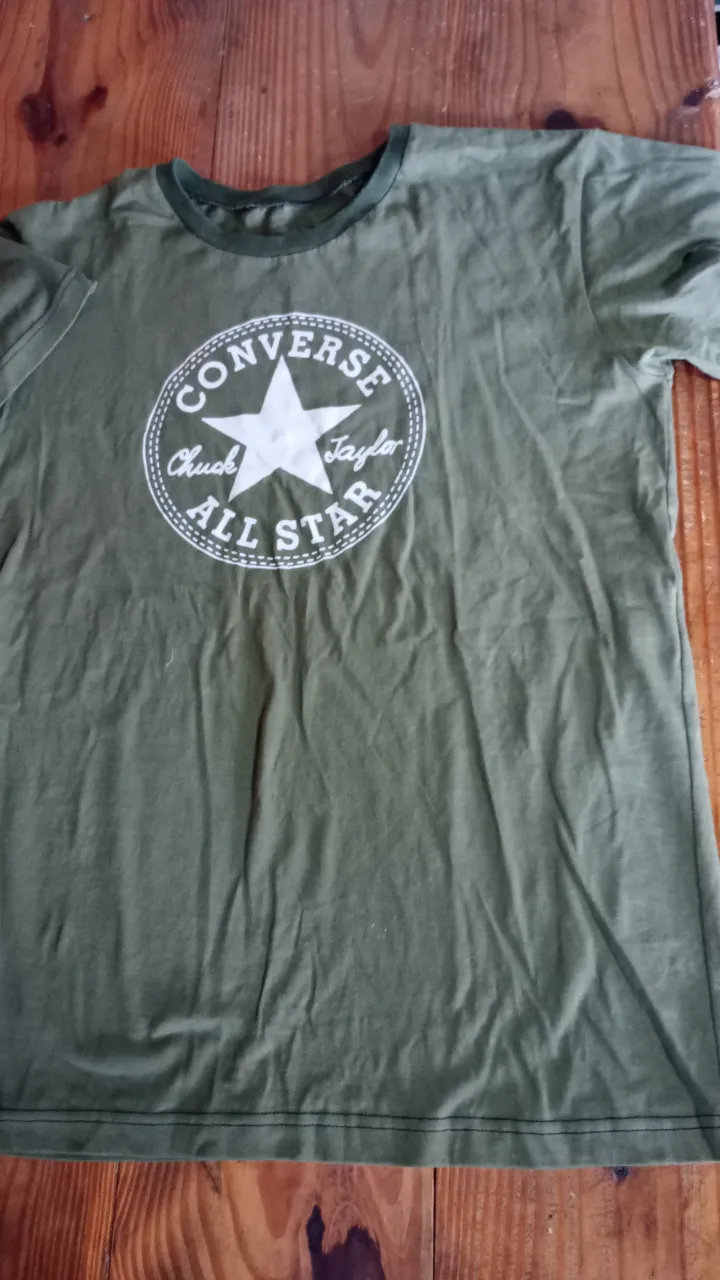 Remera de hombre Converse All Star, color verde militar, con el logo icónico estampado en el frente. Ideal para un look casual y urbano.