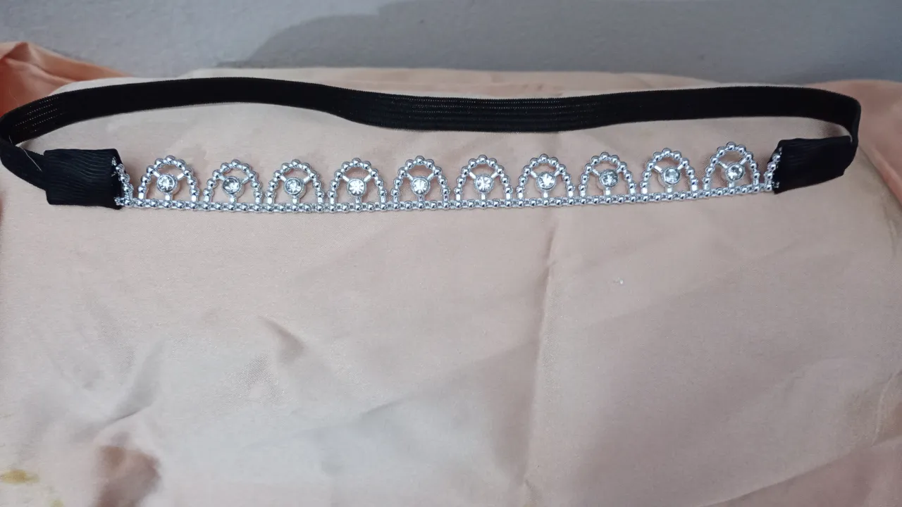 Diadema de metal plateado con detalles de strass y banda elástica negra. Ideal para eventos especiales o para darle un toque elegante a tu look.
