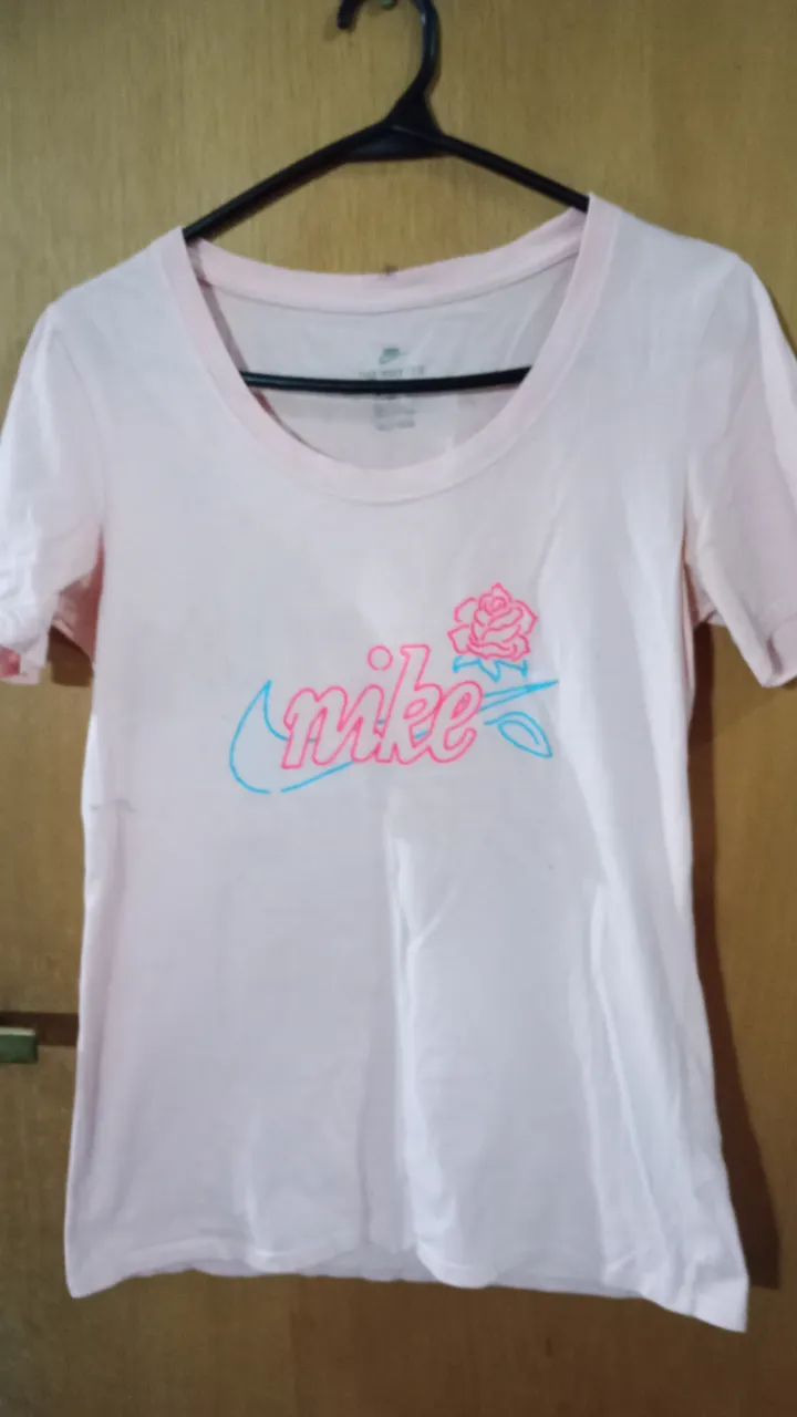 Remera Nike rosa con estampado del logo de la marca en color celeste y rosa. Ideal para un look deportivo y casual.