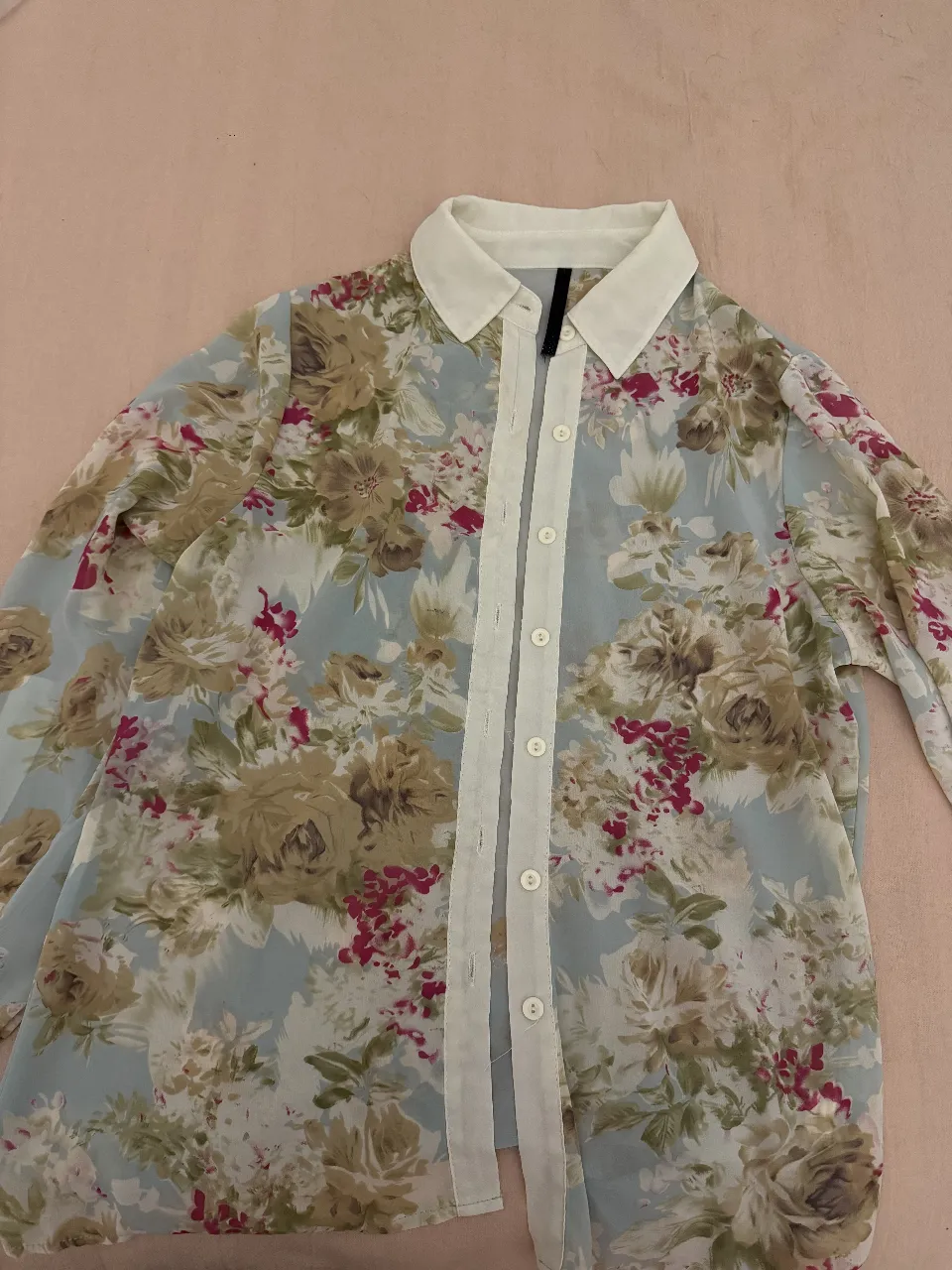Camisa de mujer con estampado floral en tonos celeste, blanco, marrón y borgoña. Diseño con cuello y botones, ideal para un look casual y femenino.