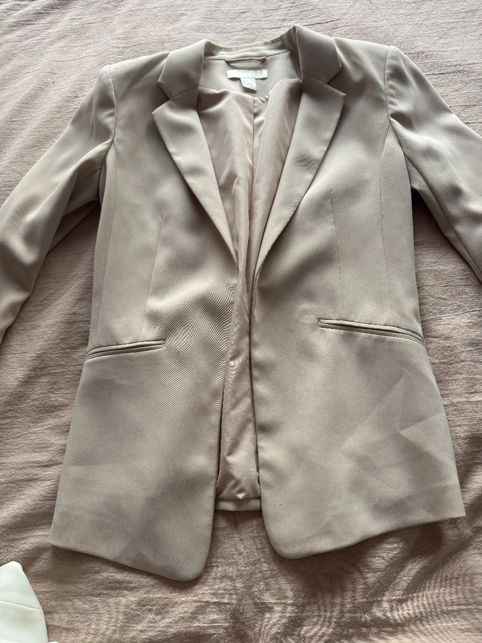 Blazer de mujer color rosa pálido, con solapas y bolsillos. Ideal para un look elegante y sofisticado. Perfecto para combinar con pantalones sastreros o jeans.