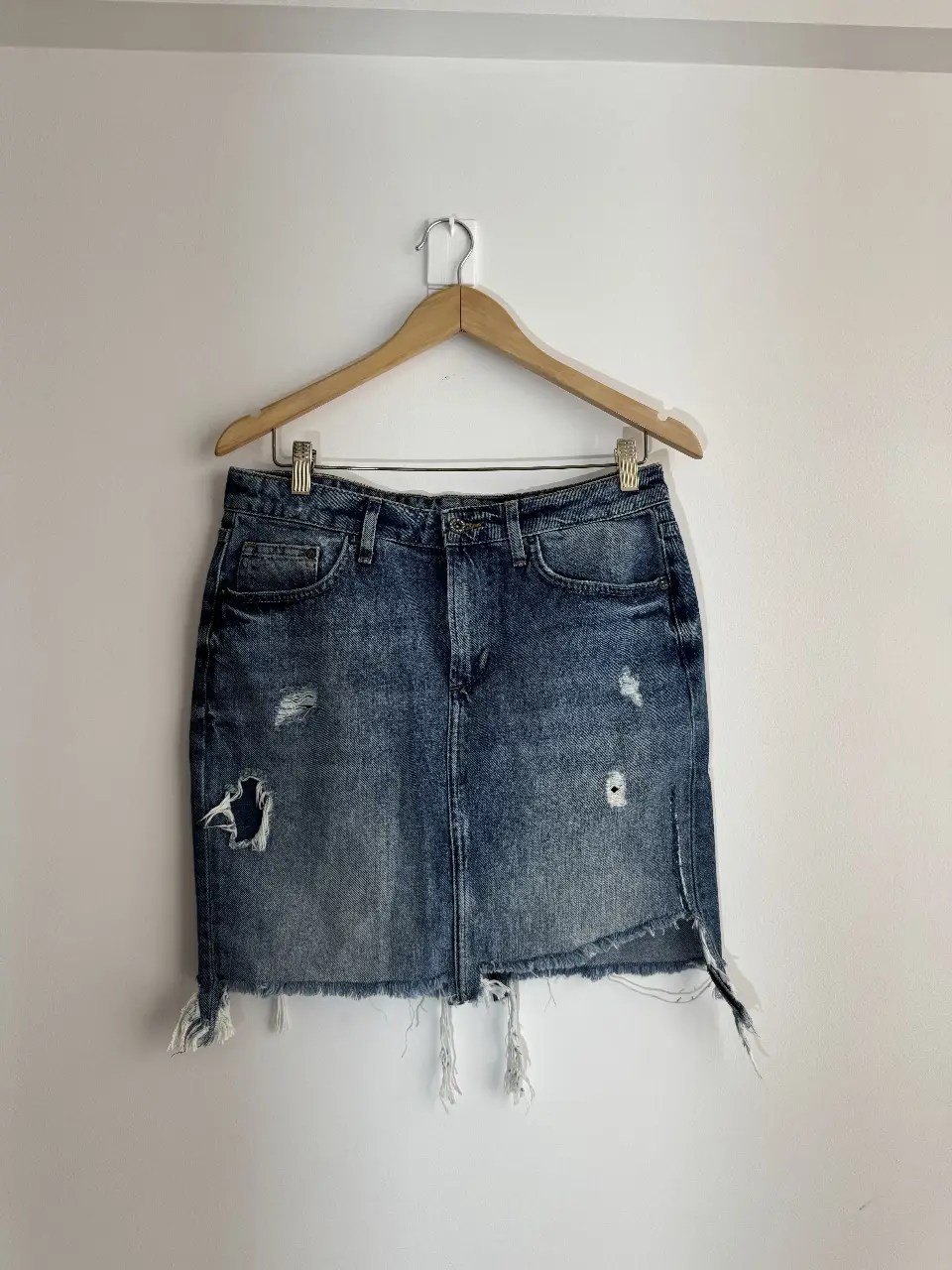 Pollera larga de jean azul con detalles rotos y flecos en el borde. Ideal para un look casual y moderno.