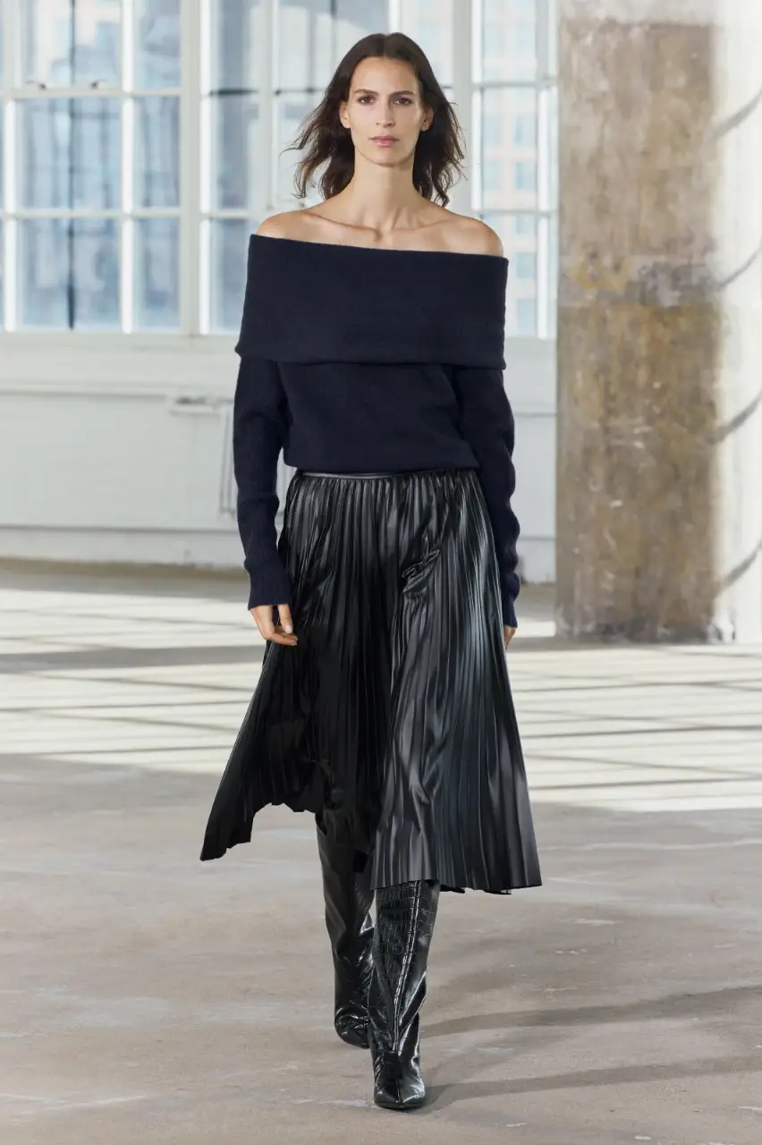Pollera midi plisada de cuero sintético, ideal para un look elegante y moderno. Perfecta para combinar con un sweater off-shoulder.