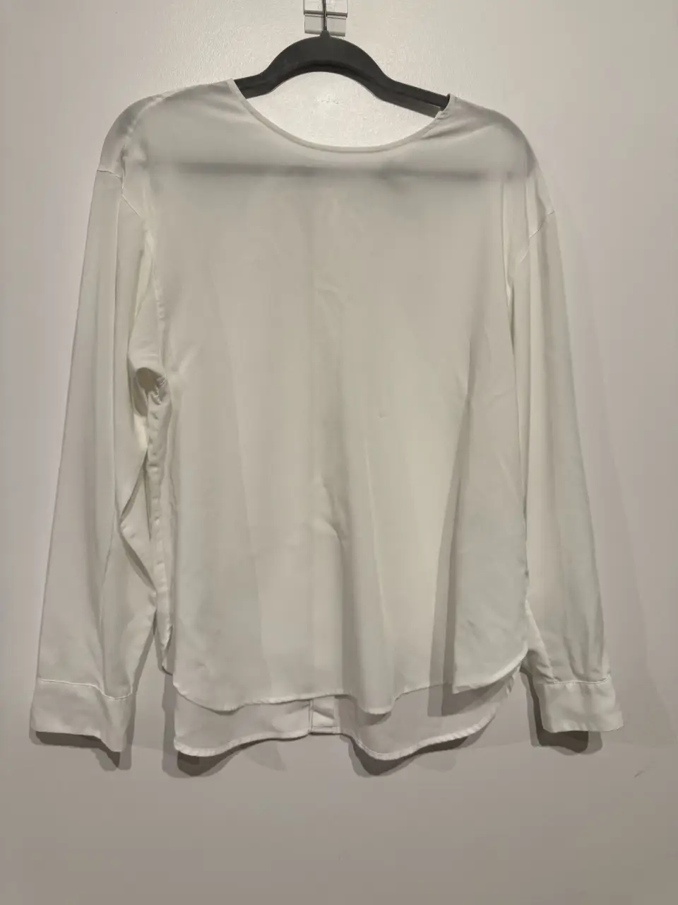 Blusa blanca de manga larga con botones en la espalda. Ideal para un look elegante y versátil.