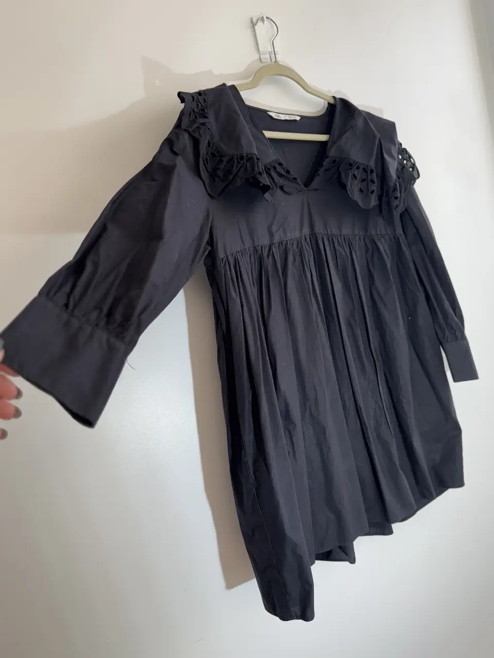 Vestido mini negro con cuello solapa y detalles calados. Ideal para un look elegante y moderno.