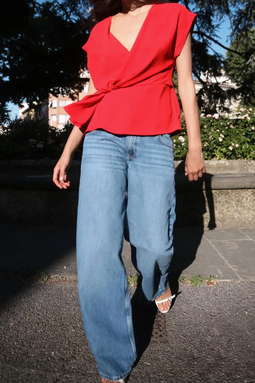 Blusa roja con diseño drapeado y detalle de nudo en la cintura. Ideal para un look elegante y moderno.