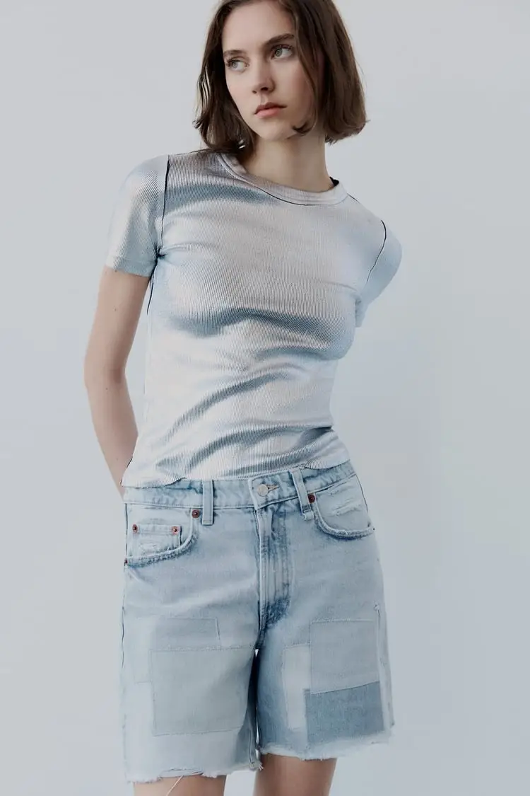 Short de jean de mujer con parches en diferentes tonos de azul. Corte clásico, tiro medio y dobladillo deshilachado. Ideal para un look casual y moderno.art 157