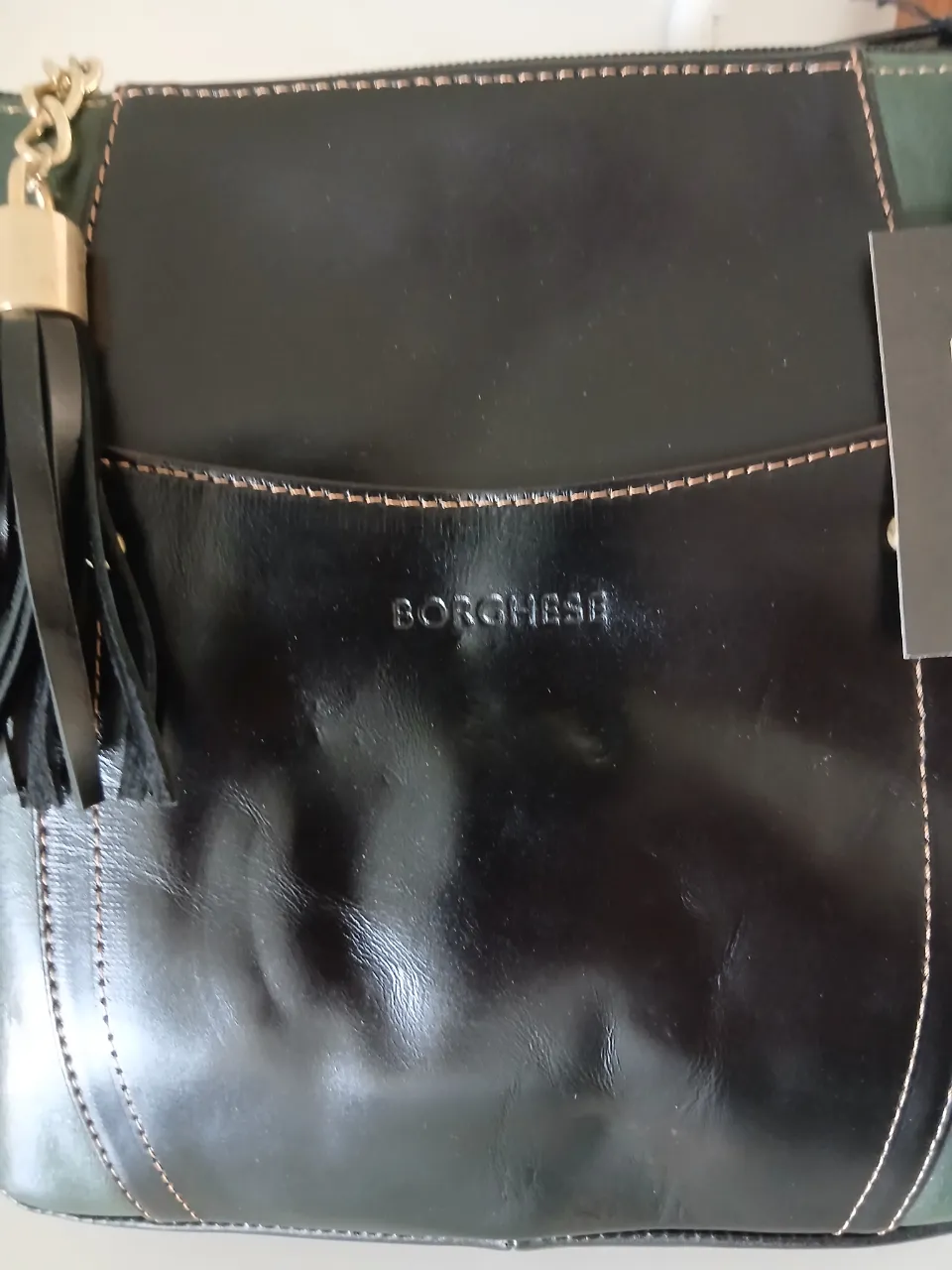 Bolso "Borghese" de cuero negro y verde. Diseño moderno con detalles en rojo y flecos. Ideal para el día a día o salidas casuales.