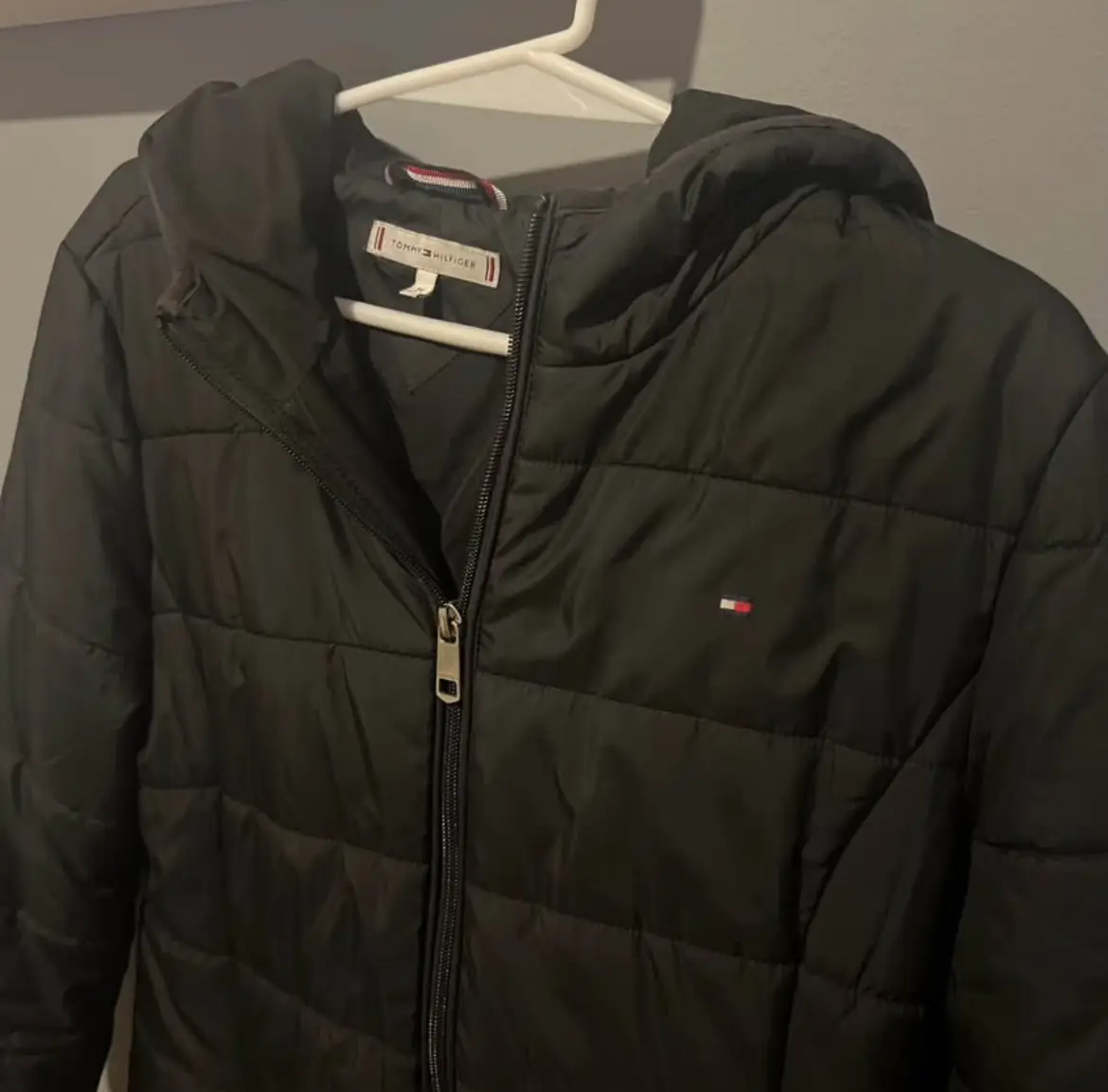 Campera Tommy Hilfiger negra con capucha, ideal para el invierno. Talle M, con cierre y logo de la marca.