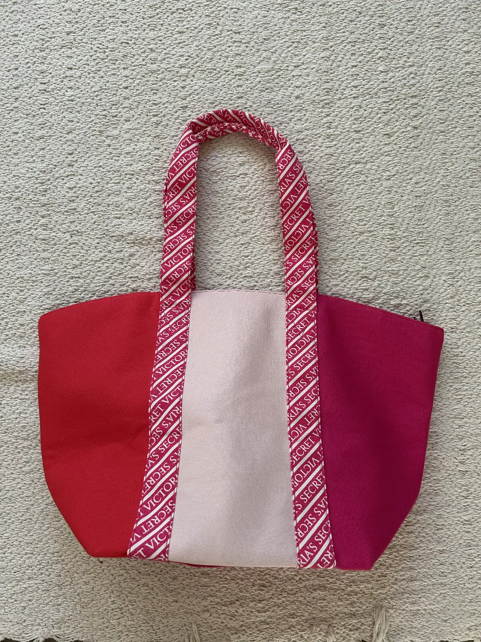 Bolso tote de Victoria's Secret, con diseño a bloques en rojo y rosa, con detalles del logo de la marca en las manijas. Ideal para llevar tus esenciales con estilo.