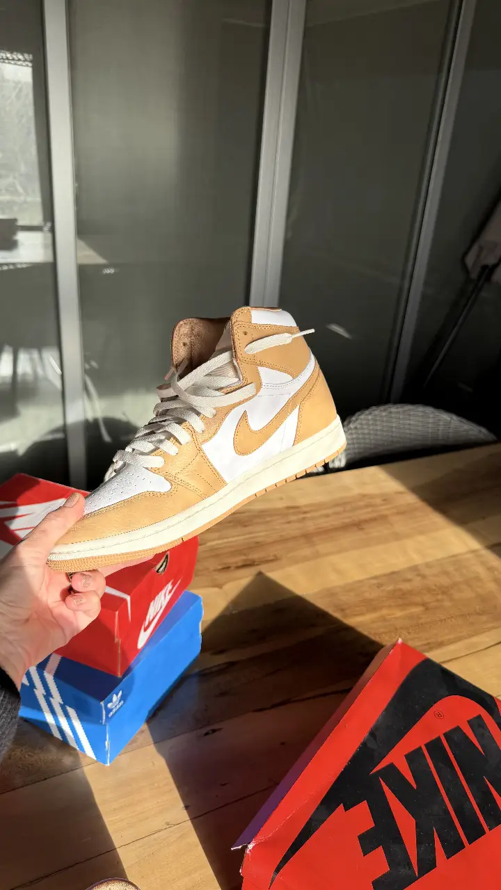 Zapatillas Nike Air Jordan 1 High, color beige y blanco, con el logo de la marca en el lateral. Ideales para un look casual y urbano.