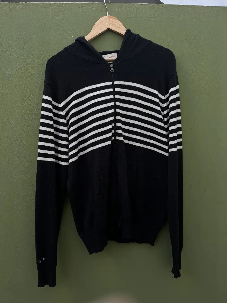 Buzo con cierre y capucha, de color negro con franjas blancas horizontales. Marca Old Bridge, talle M.