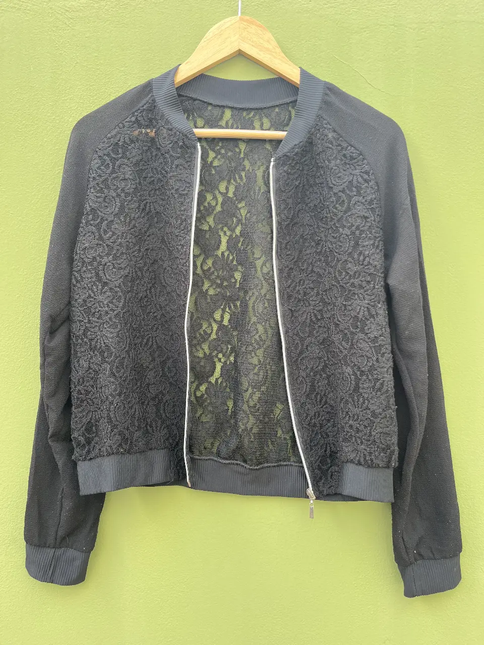 Campera negra con detalles de encaje floral. Ideal para un look elegante y moderno. Cierre frontal y puños tejidos.