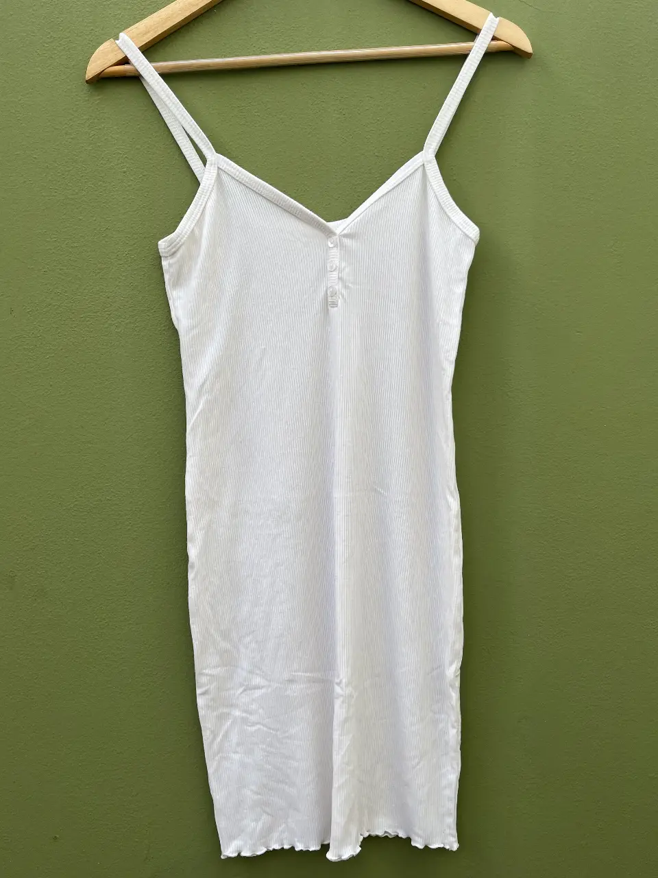 Vestido mini blanco de tirantes finos, con detalle de botones en el frente y corte ajustado. Tela Morley