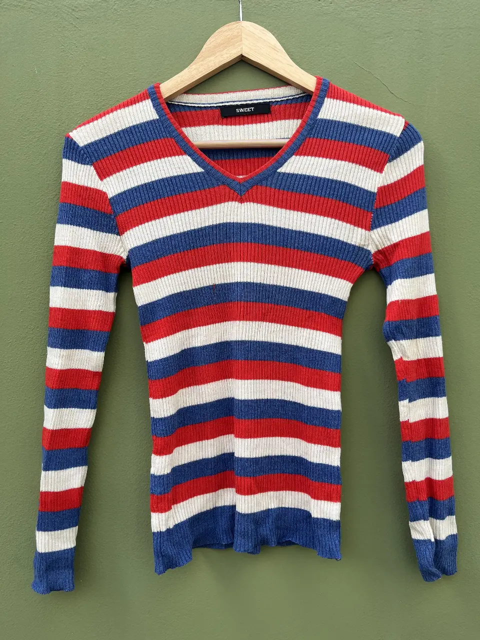 Sweater finito con rayas horizontales en rojo, blanco y azul. Cuello en V. Marca SWEET. Tiene un pequeño detalle (foto 3).