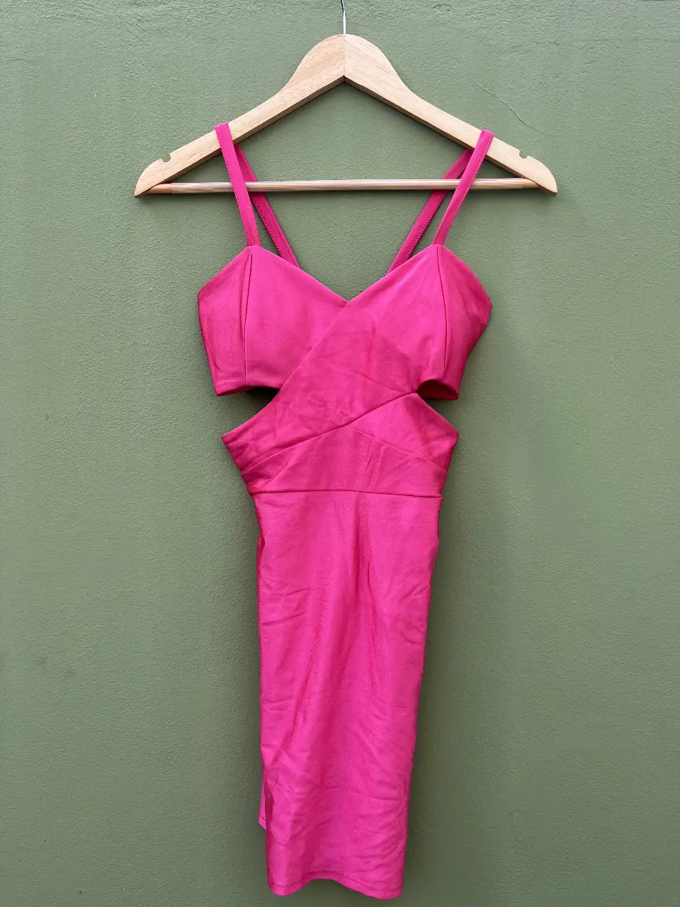Vestido mini fucsia con cortes a los lados y tiras finas. Ideal para una fiesta o salida nocturna.