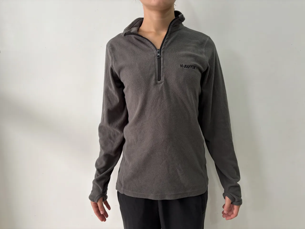 Remera de polar gris con cierre en el cuello y logo bordado. Ideal para actividades al aire libre o para un look casual y cómodo.