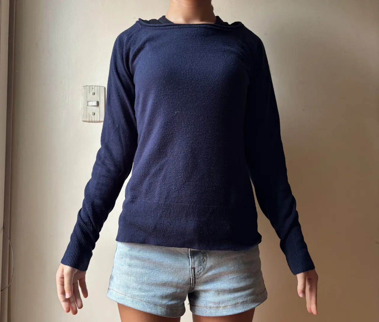 Sweater azul marino de manga larga, con cuello redondo y detalles de tejido acanalado en puños y cintura. Ideal para un look casual y cómodo.