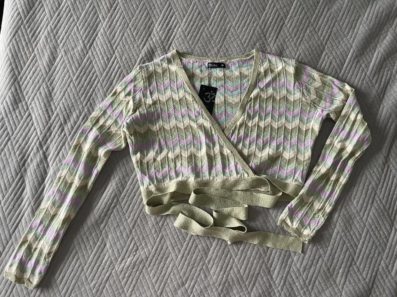 Cárdigan tejido con diseño chevron en tonos verde, lila y blanco. Ideal para un look casual y moderno.