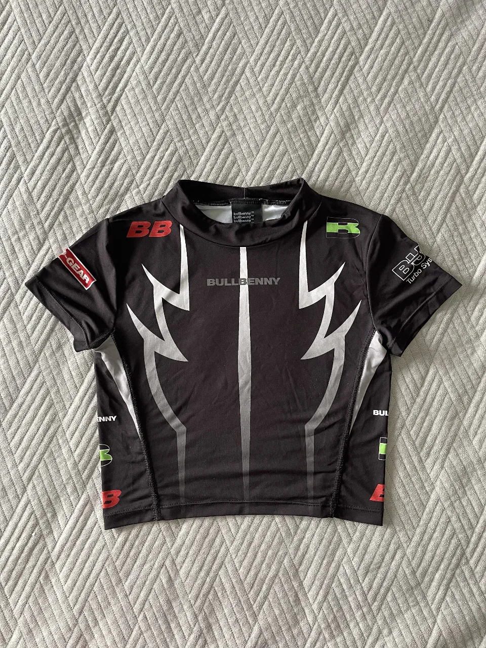 Remera deportiva de manga corta para mujer, con cuello alto y diseño con detalles en blanco y verde. Ideal para entrenamientos y actividades físicas. Marca Bullbenny.