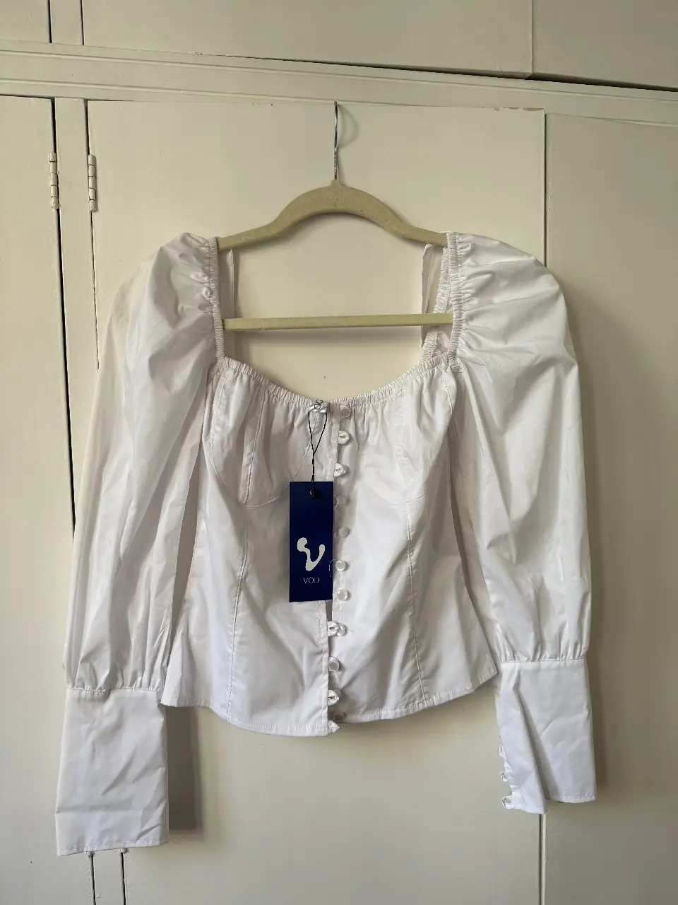 Camisa blanca marca VÖD con mangas largas abullonadas y botones delanteros. Cuello cuadrado y detalles de costura. Ideal para un look elegante y moderno. Se puede usar de los dos lados. La marca la vende a $90.000. Dice talle M pero es para S. 