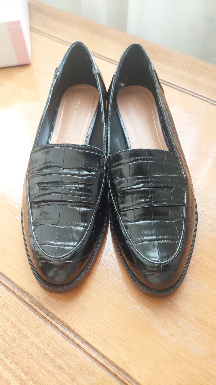 Mocasines negros de charol con diseño de cocodrilo, ideales para un look elegante y sofisticado. Perfectos para combinar con diferentes outfits.