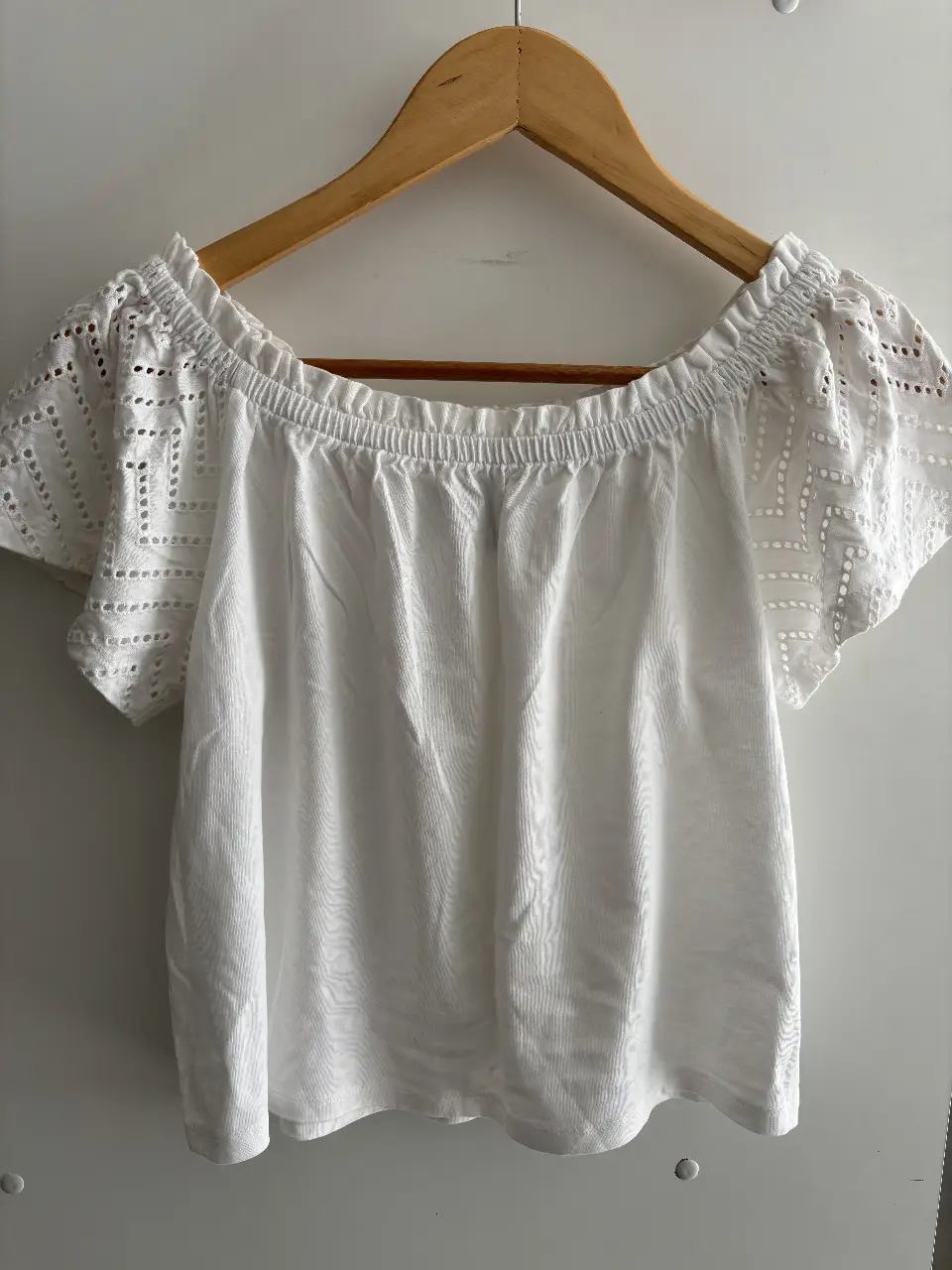 Blusa blanca con mangas cortas y detalles de encaje. Cuello estilo off-shoulder con elástico. Ideal para un look fresco. PRIMARK 