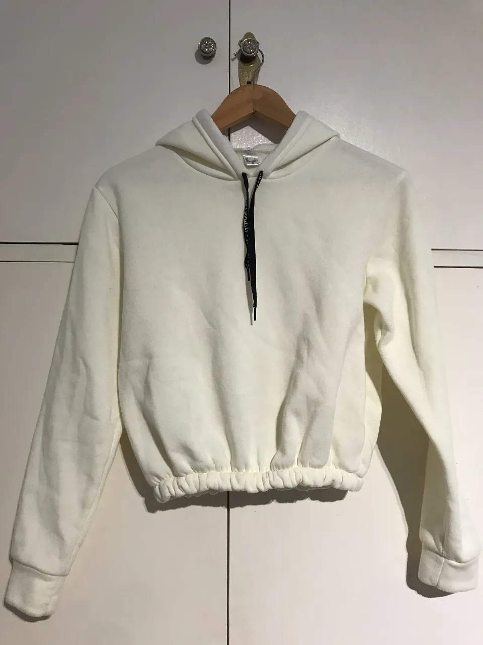 Buzo crop blanco con capucha y ajuste en la cintura. Ideal para un look casual y cómodo.