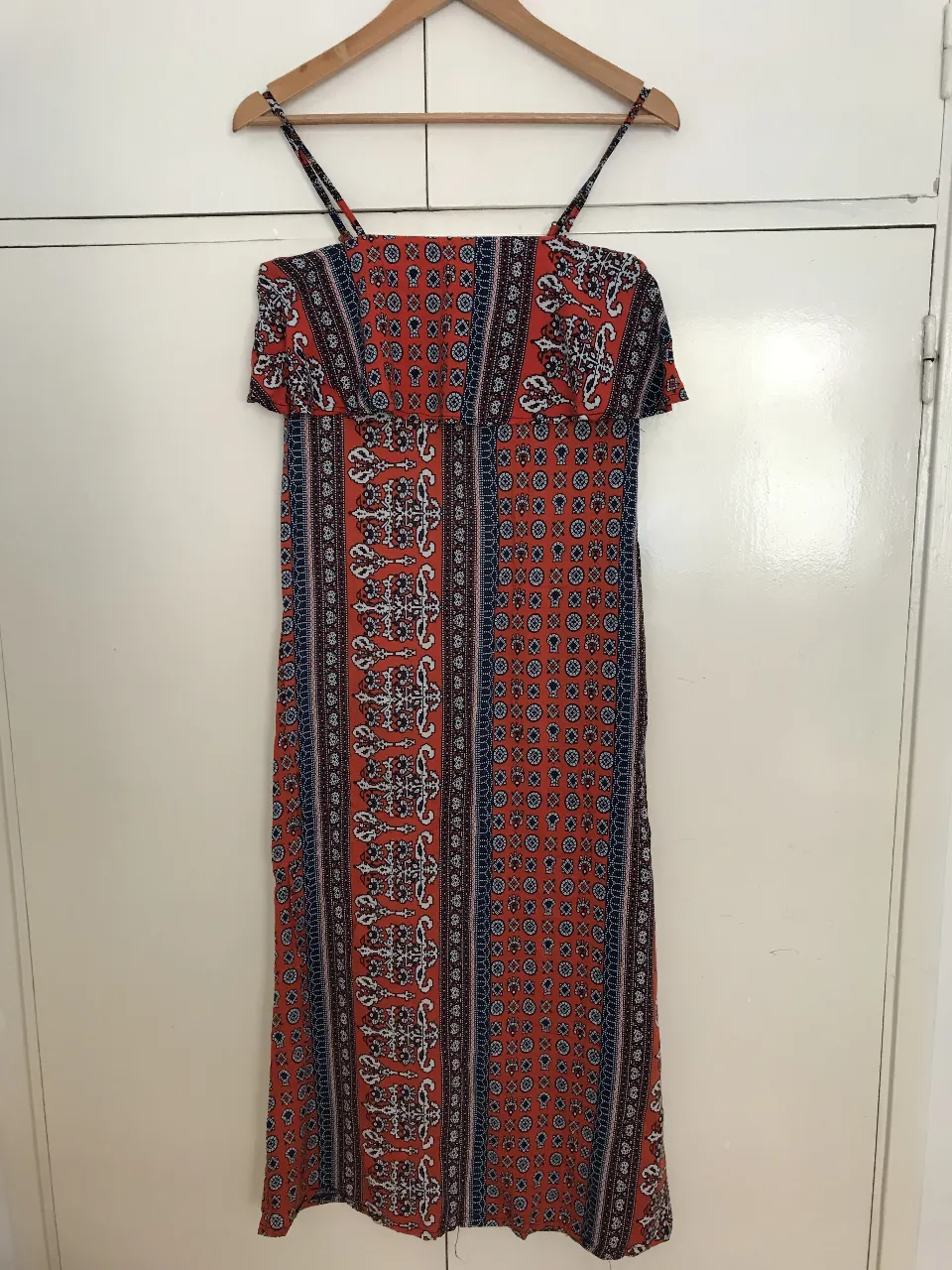 Vestido largo de mujer con estampado floral en tonos rojos y azules. Diseño con tirantes finos y volantes en el escote. Ideal para un look fresco y bohemio.