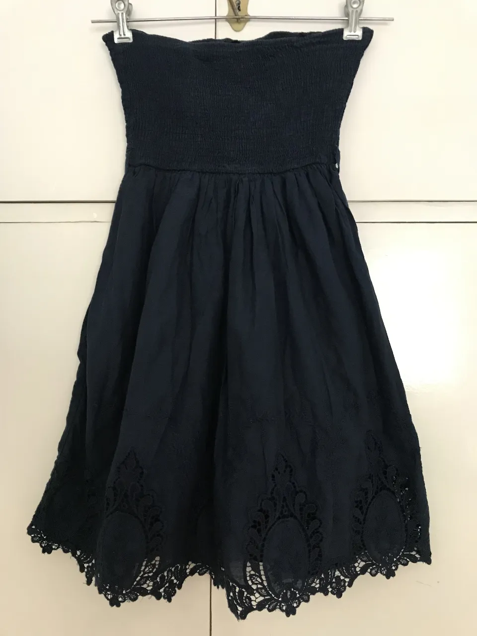 Vestido mini strapless de color azul marino con detalles de encaje en el borde inferior. Ideal para una salida casual o una fiesta.