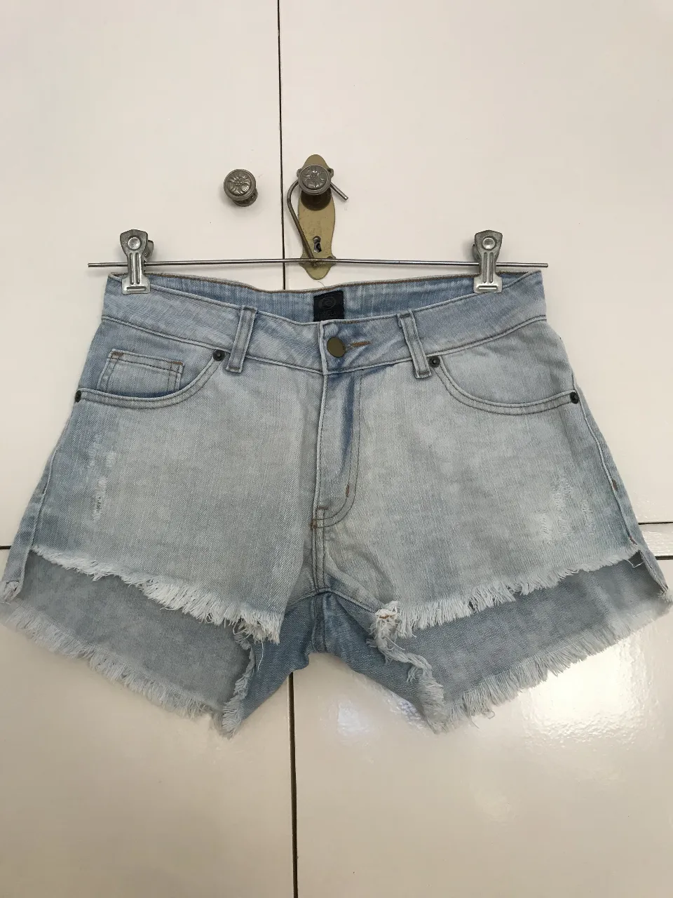Short de jean celeste con detalles rotos y flecos en el borde. Tiro medio, ideal para un look casual y fresco. Marca Rip Curl.