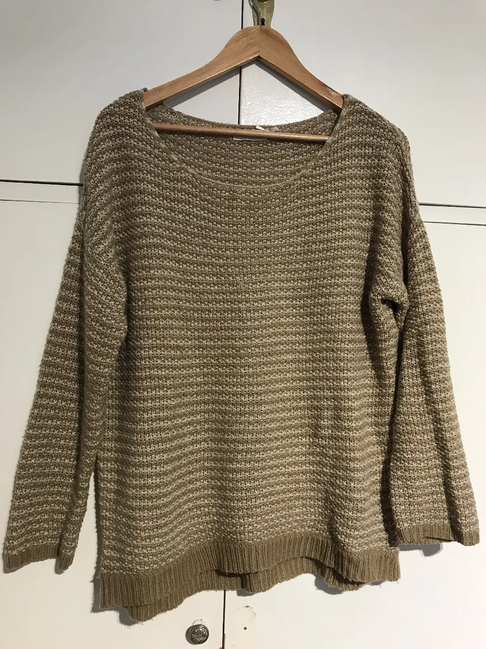 Sweater tejido de color crudo y marrón, con cuello redondo y mangas largas. Ideal para un look casual y abrigado.