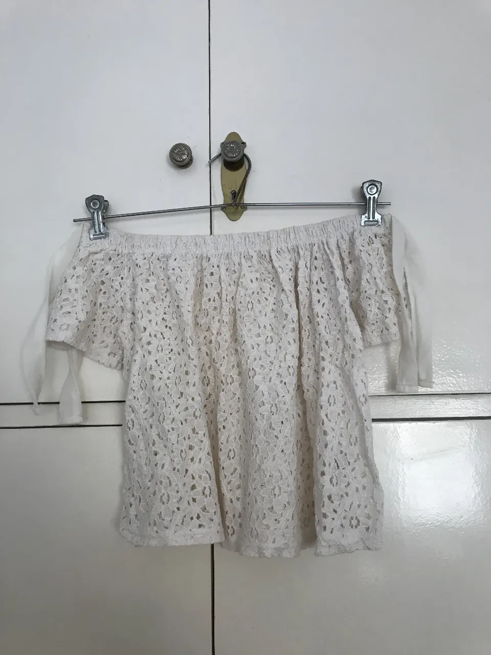 Blusa de encaje blanco, estilo off-shoulder con detalles de lazos en las mangas. Ideal para un look fresco y femenino.