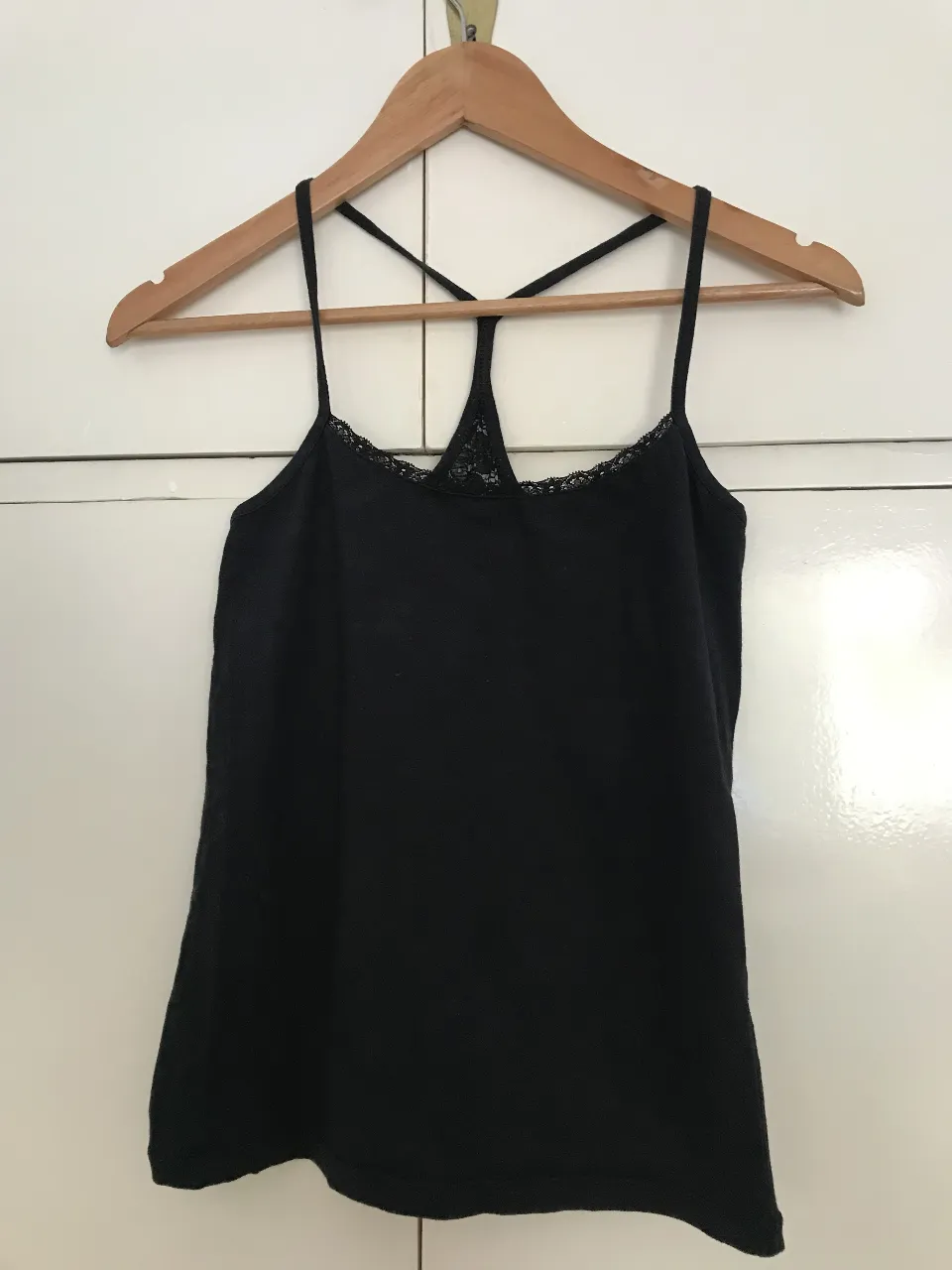 Top negro con detalle de encaje en el escote y espalda.  Ideal para combinar con jeans o faldas para un look casual y moderno.